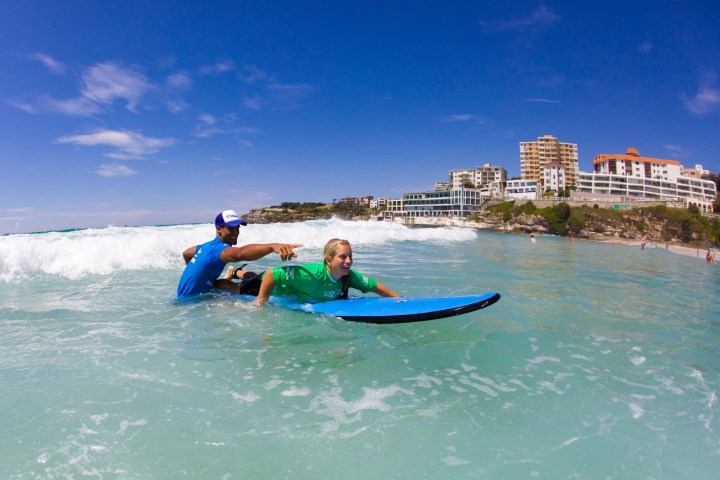 A woman being taught to surf on Bondi Beach