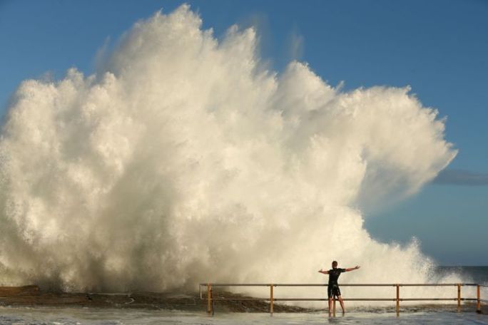 A man waiting for a massive wave to crash into him.